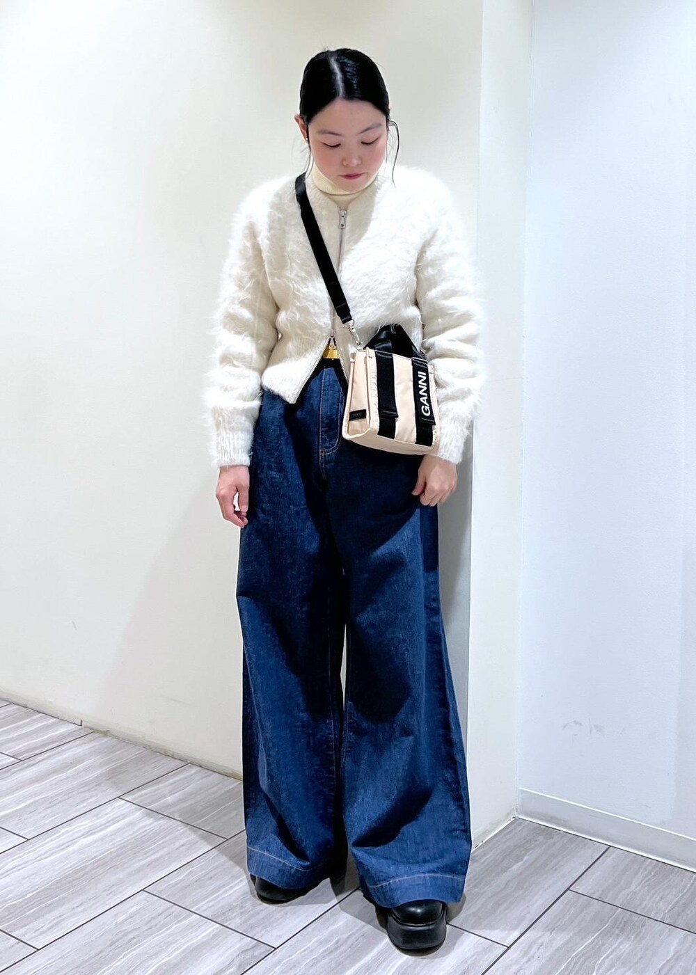 ベージュ系のトートバッグ、ブラック系のサンダル、ホワイト系のカーディガン/ボレロを着用したレディースの冬コーディネートの2枚目の写真