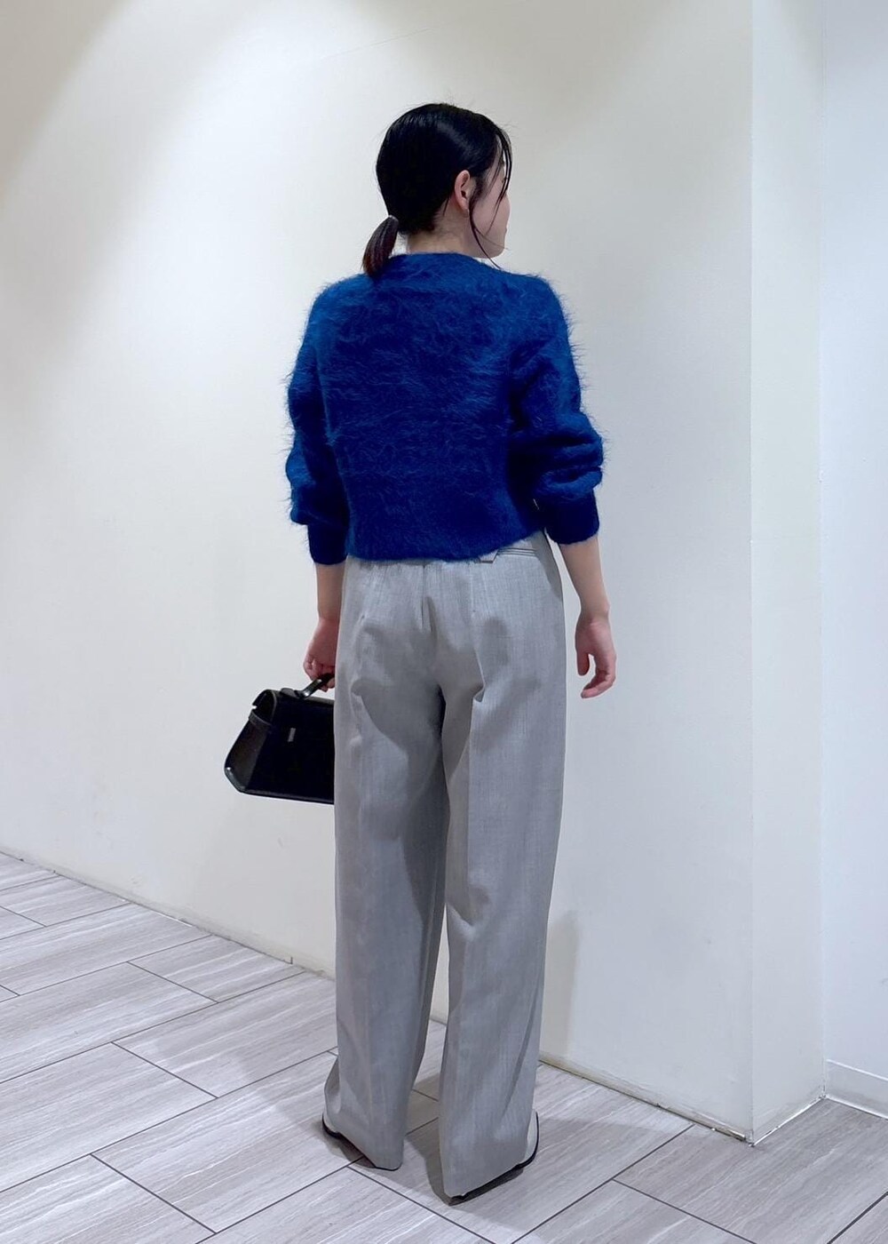 シルバー系のブーツ、ブルー系のカーディガン/ボレロ、グレー系のスラックスを着用したレディースの秋コーディネートの3枚目の写真