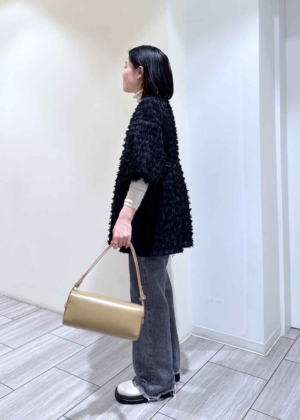 ホワイト系のブーツ、グレー系のデニムパンツ、ベージュ系のハンドバッグを着用したレディースの冬コーディネートの3枚目の写真