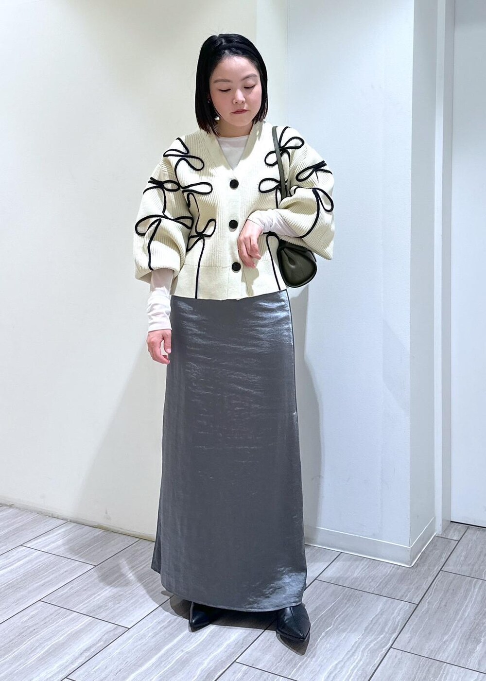 ホワイト系のカーディガン/ボレロ、ブラック系のブーツ、ホワイト系のTシャツ/カットソーを着用したレディースの秋コーディネートの6枚目の写真