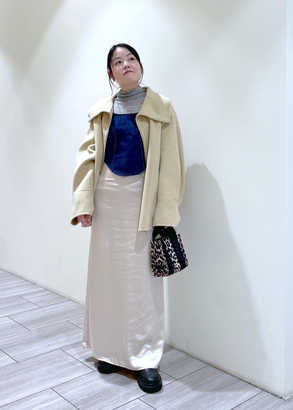 ベージュ系のトートバッグ、ブラック系のブーツ、ホワイト系のスカートを着用したレディースの秋コーディネートの2枚目の写真