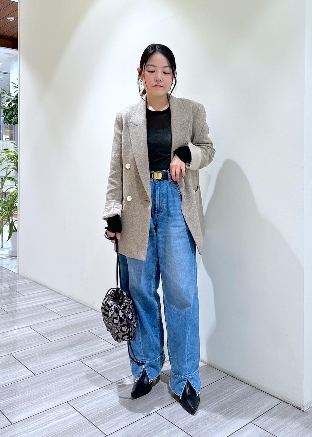 ブルー系のデニムパンツ、ブラック系のブーツ、グレー系のハンドバッグを着用したレディースの秋コーディネートの7枚目の写真