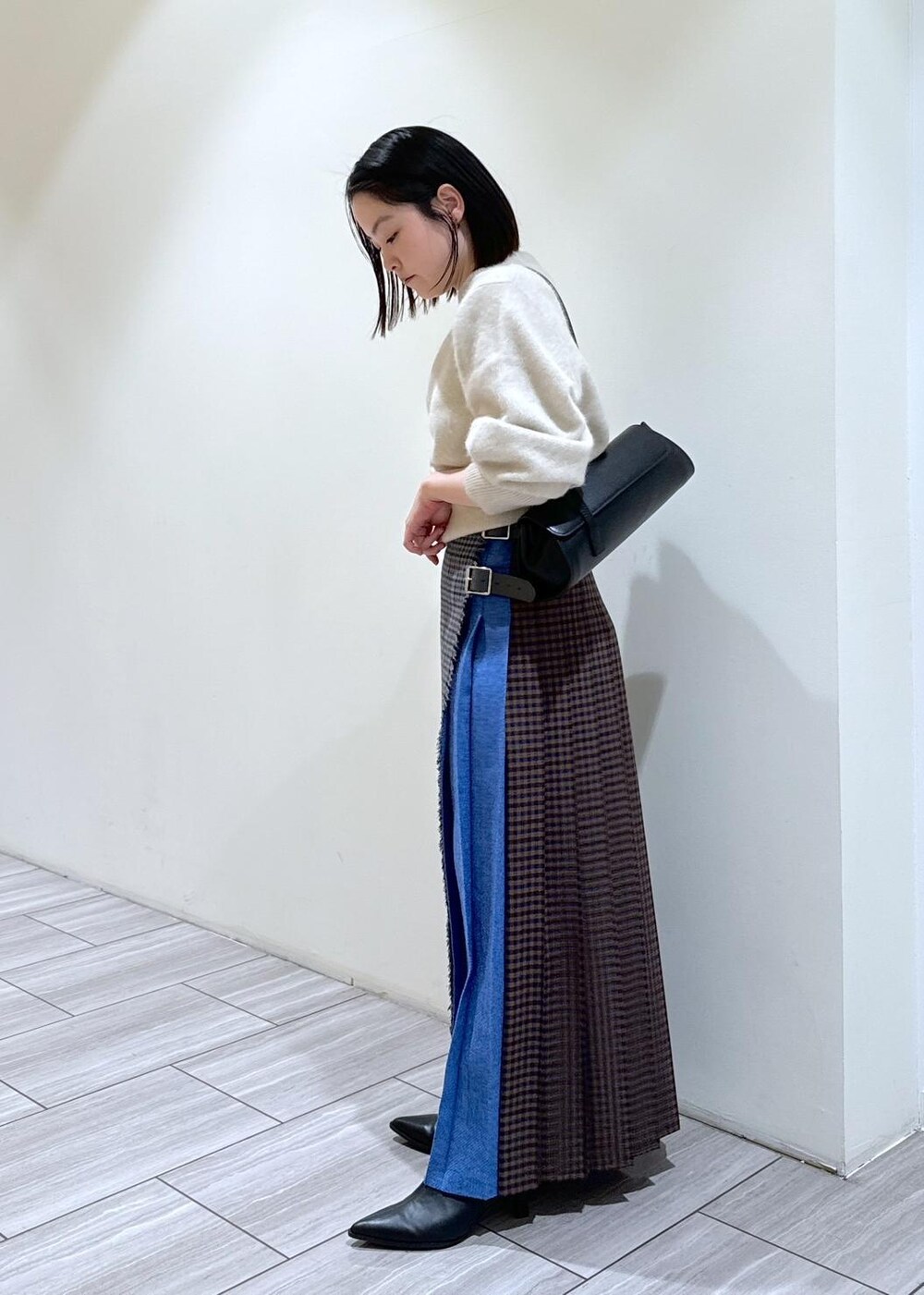 ブラック系のブーツ、ブラック系のショルダーバッグ、ホワイト系のニット/セーターを着用したレディースの秋コーディネートの2枚目の写真