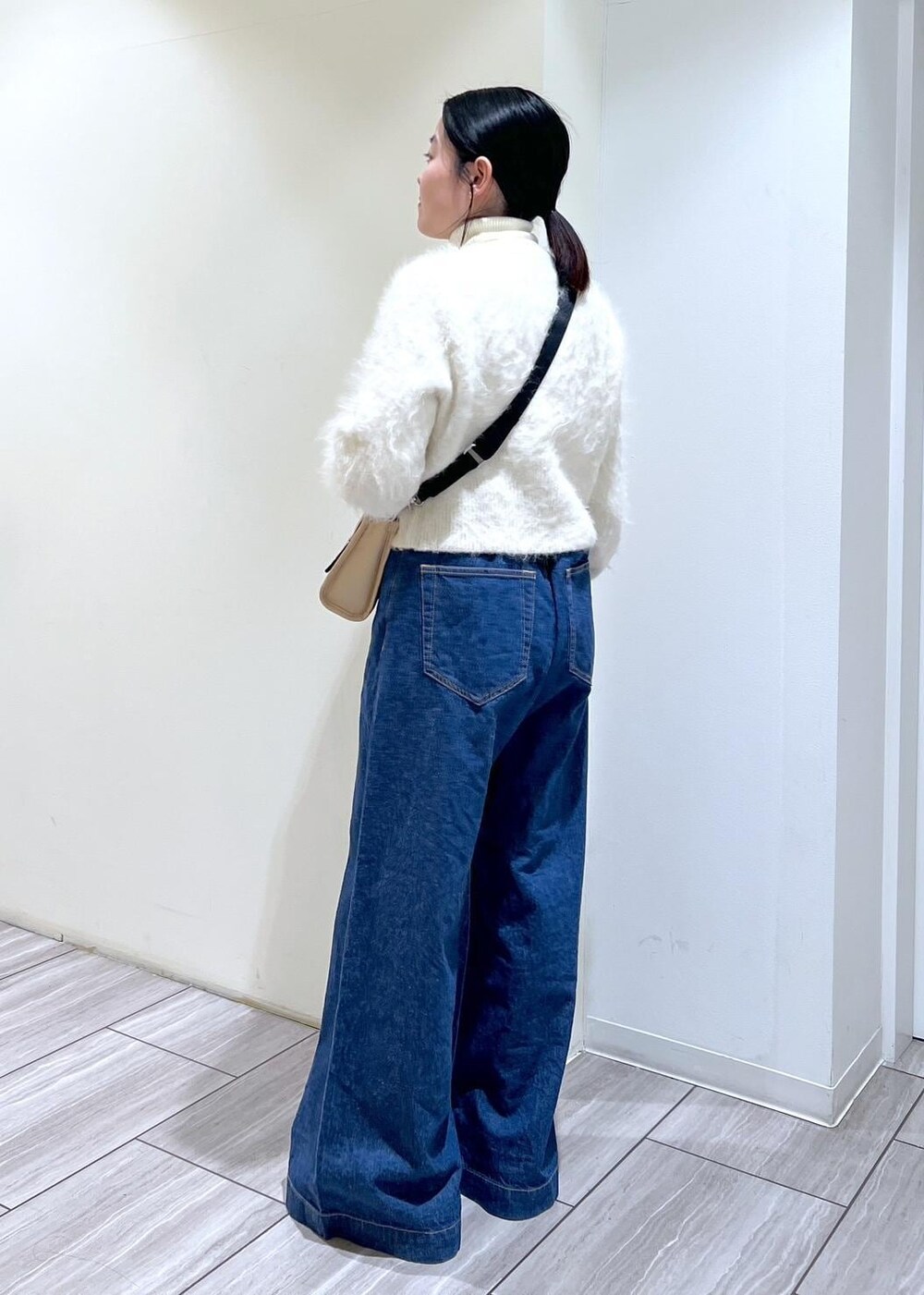 ベージュ系のトートバッグ、ブラック系のサンダル、ホワイト系のカーディガン/ボレロを着用したレディースの冬コーディネートの3枚目の写真