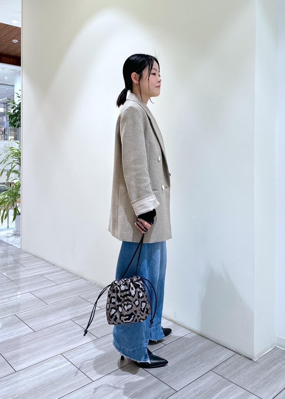 ブルー系のデニムパンツ、ブラック系のブーツ、グレー系のハンドバッグを着用したレディースの秋コーディネートの4枚目の写真