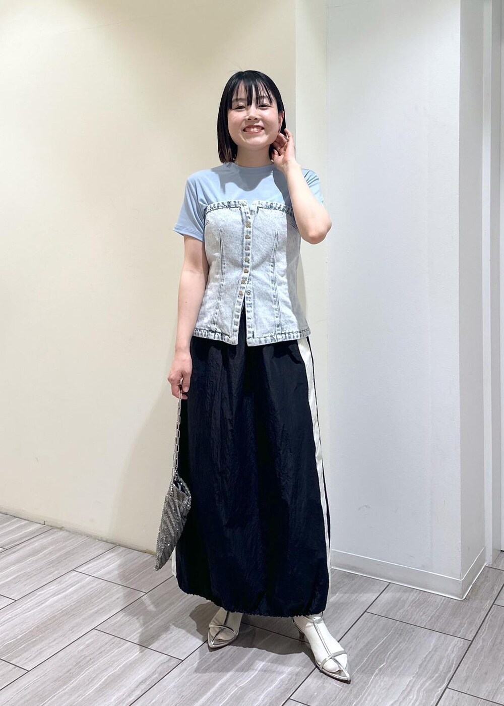 シルバー系のハンドバッグ、シルバー系のサンダル、ブラック系のスカートを着用したレディースの夏コーディネートの5枚目の写真