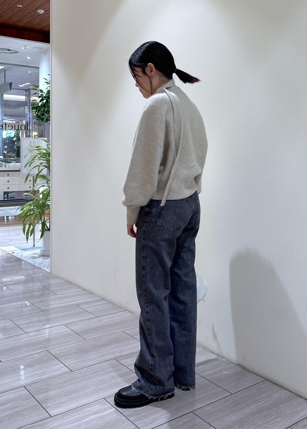 ホワイト系のカーディガン/ボレロ、ブラック系のブーツ、グレー系のデニムパンツを着用したレディースの秋コーディネートの3枚目の写真