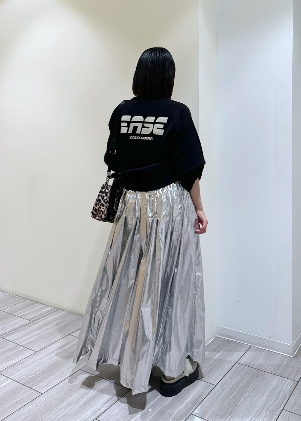 ベージュ系のサンダル、ベージュ系のトートバッグ、シルバー系のスカートを着用したレディースの秋コーディネートの4枚目の写真