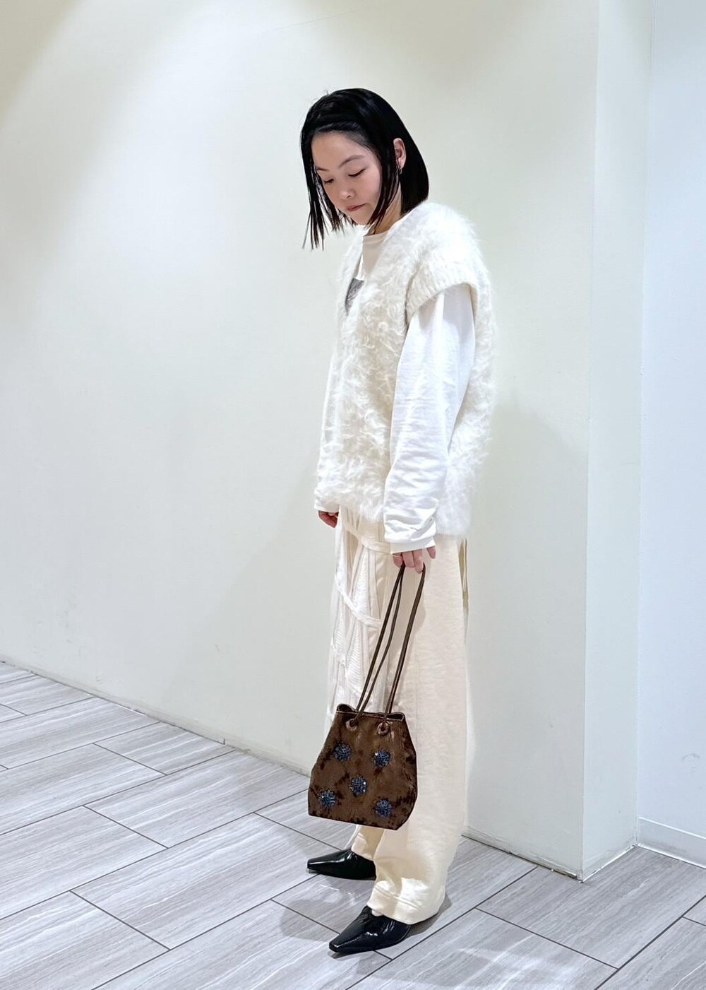 ブラック系のパンプス、ホワイト系のスカート、ホワイト系のニット/セーターを着用したレディースの秋コーディネートの2枚目の写真