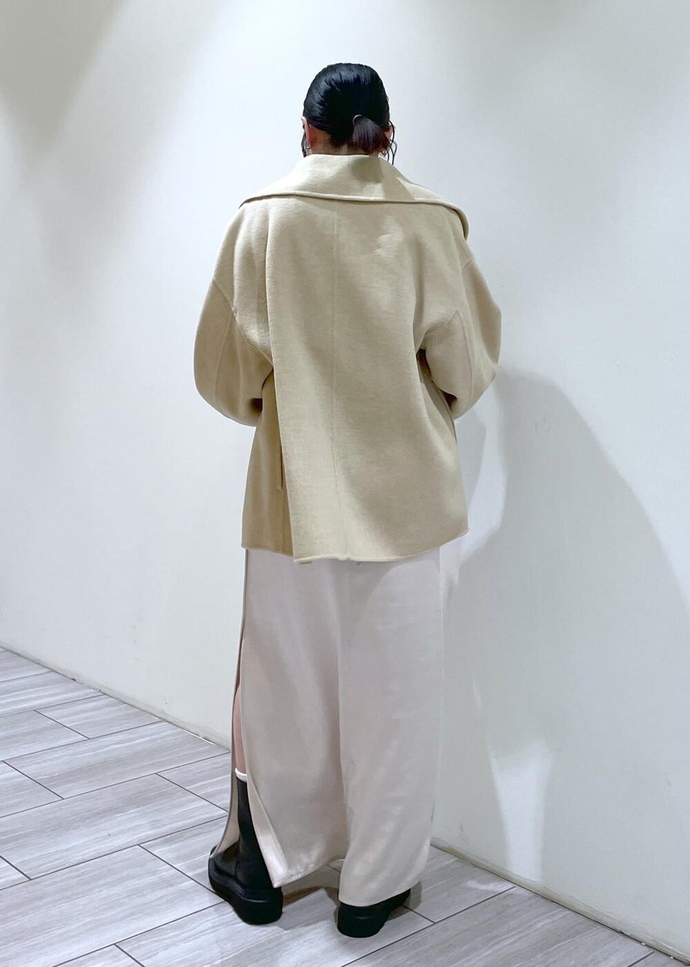 ベージュ系のトートバッグ、ブラック系のブーツ、ホワイト系のスカートを着用したレディースの秋コーディネートの4枚目の写真