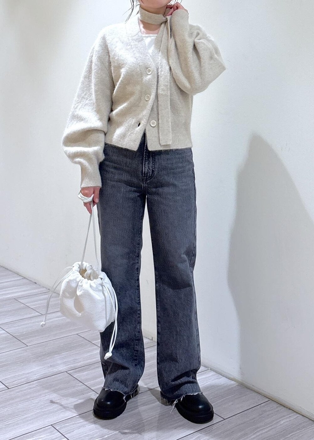 ホワイト系のカーディガン/ボレロ、ブラック系のブーツ、グレー系のデニムパンツを着用したレディースの秋コーディネートの7枚目の写真