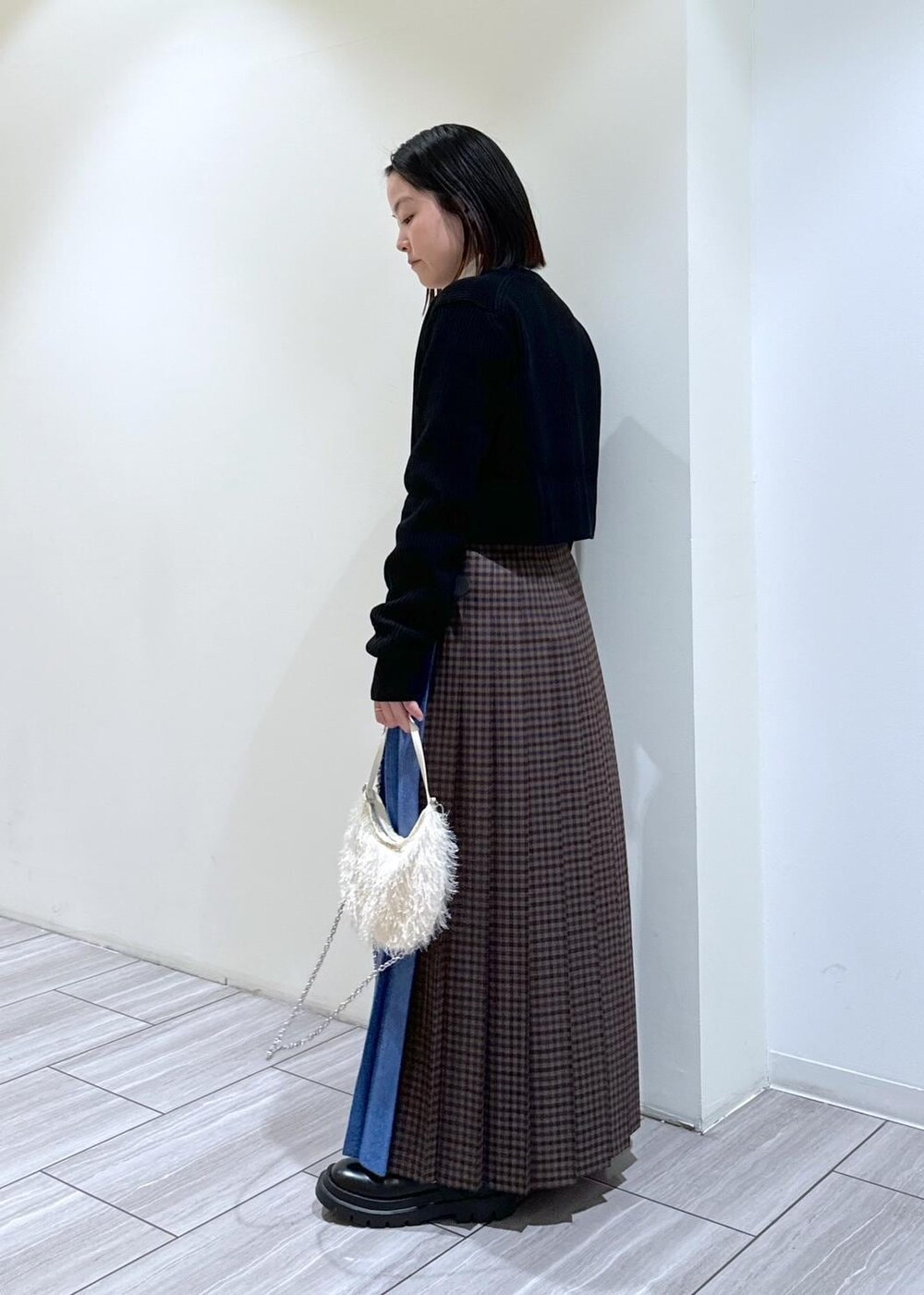 ブラック系のその他シューズ、グレー系のスカート、ホワイト系のニット/セーターを着用したレディースの秋コーディネートの3枚目の写真