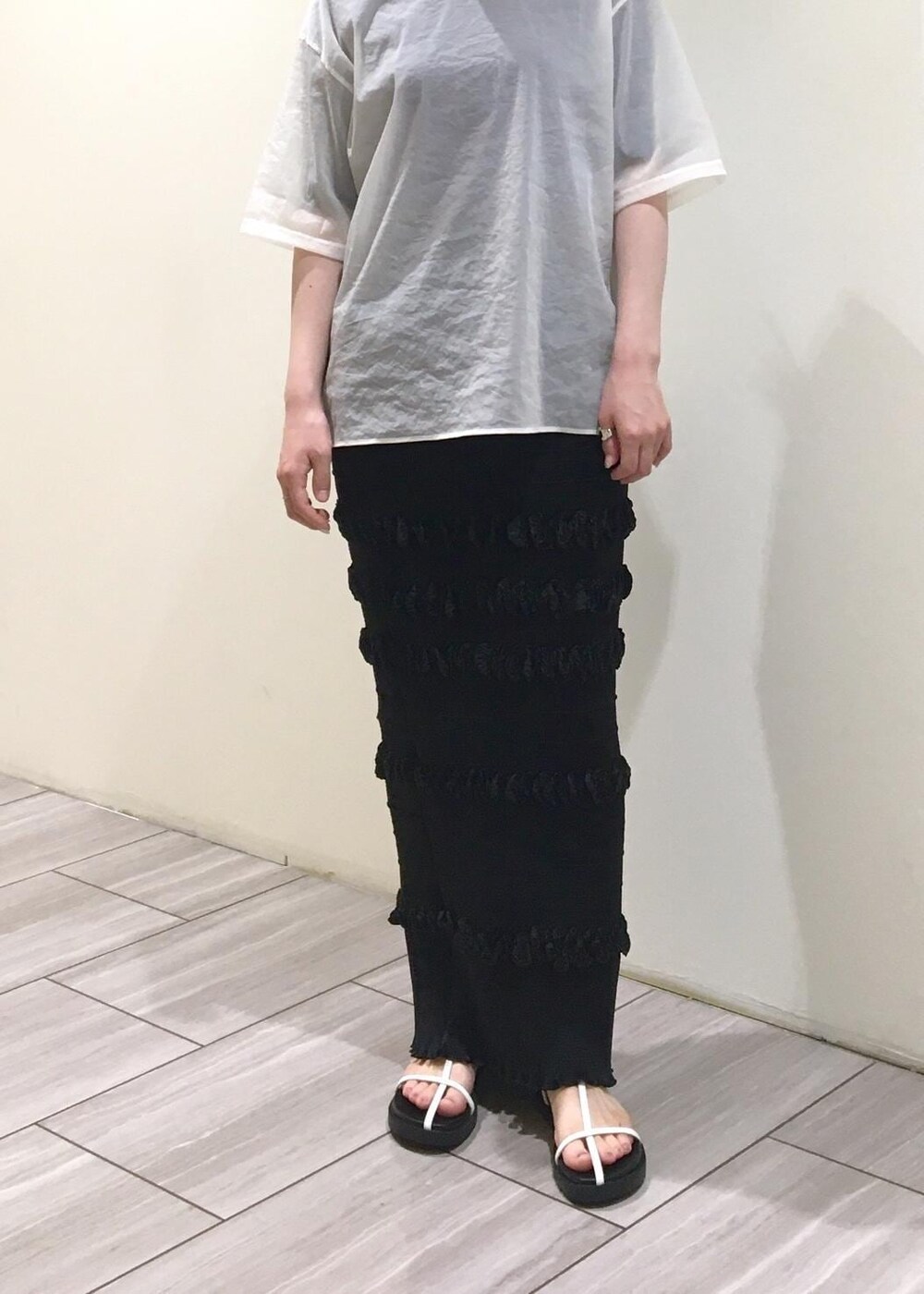 ブラック系のサンダル、ホワイト系のTシャツ/カットソー、ブラック系のスカートを着用したレディースの夏コーディネートの2枚目の写真