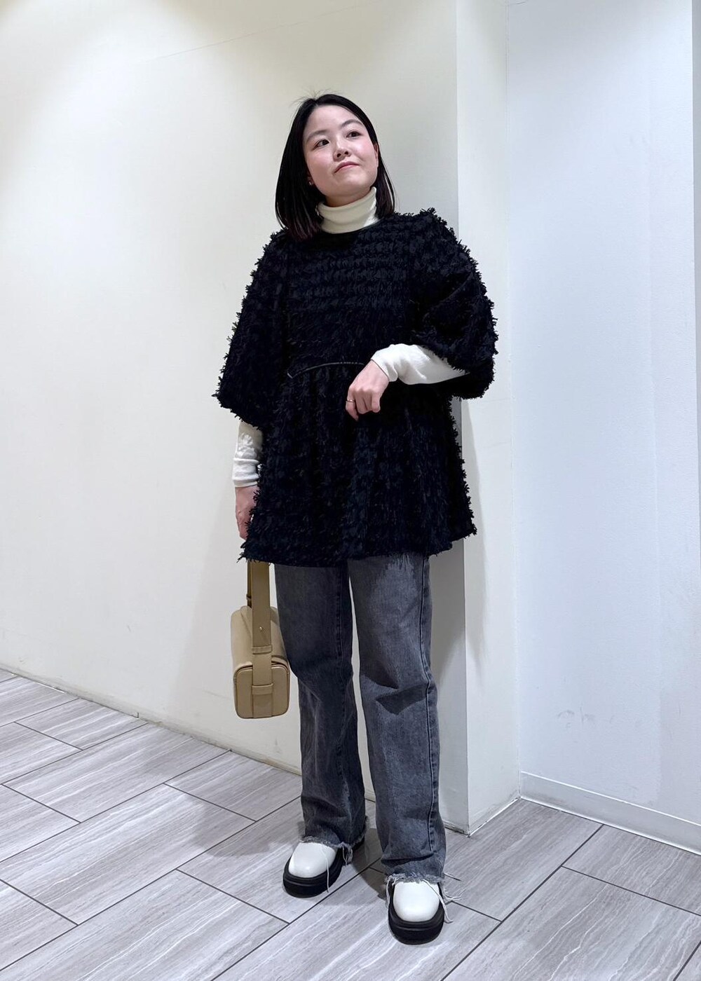 ホワイト系のブーツ、グレー系のデニムパンツ、ベージュ系のハンドバッグを着用したレディースの冬コーディネートの2枚目の写真