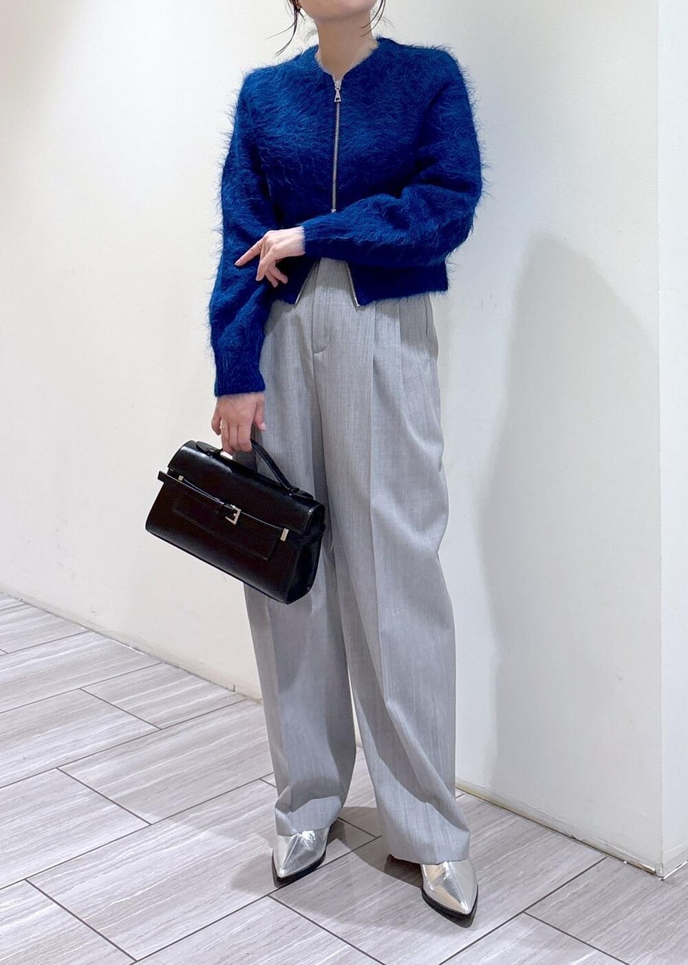 シルバー系のブーツ、ブルー系のカーディガン/ボレロ、グレー系のスラックスを着用したレディースの秋コーディネートの5枚目の写真