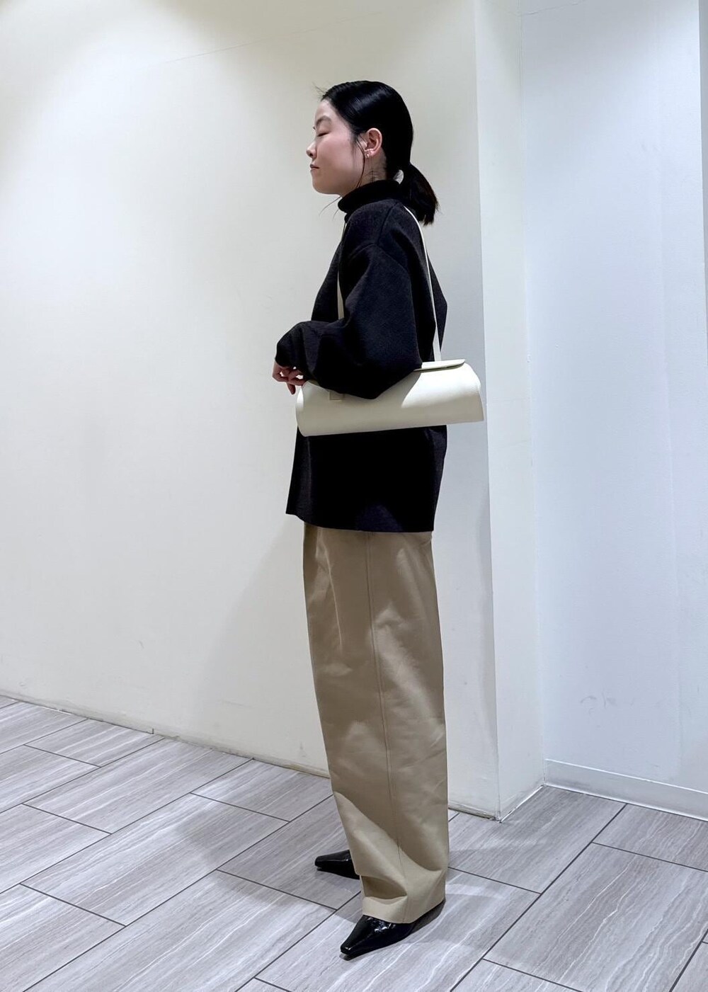 ブラック系のパンプス、グレー系のカーディガン/ボレロ、ホワイト系のショルダーバッグを着用したレディースの冬コーディネートの3枚目の写真