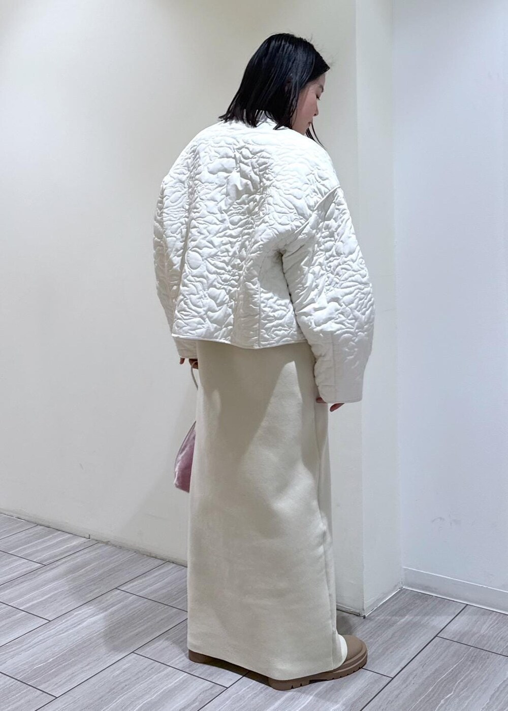 ベージュ系のブーツ、ホワイト系のブルゾン、ホワイト系のワンピースを着用したレディースの冬コーディネートの2枚目の写真