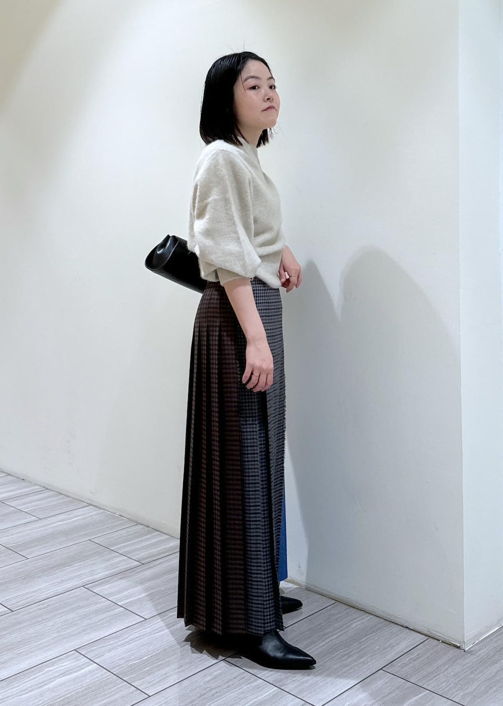 ブラック系のブーツ、ブラック系のショルダーバッグ、ホワイト系のニット/セーターを着用したレディースの秋コーディネートの4枚目の写真