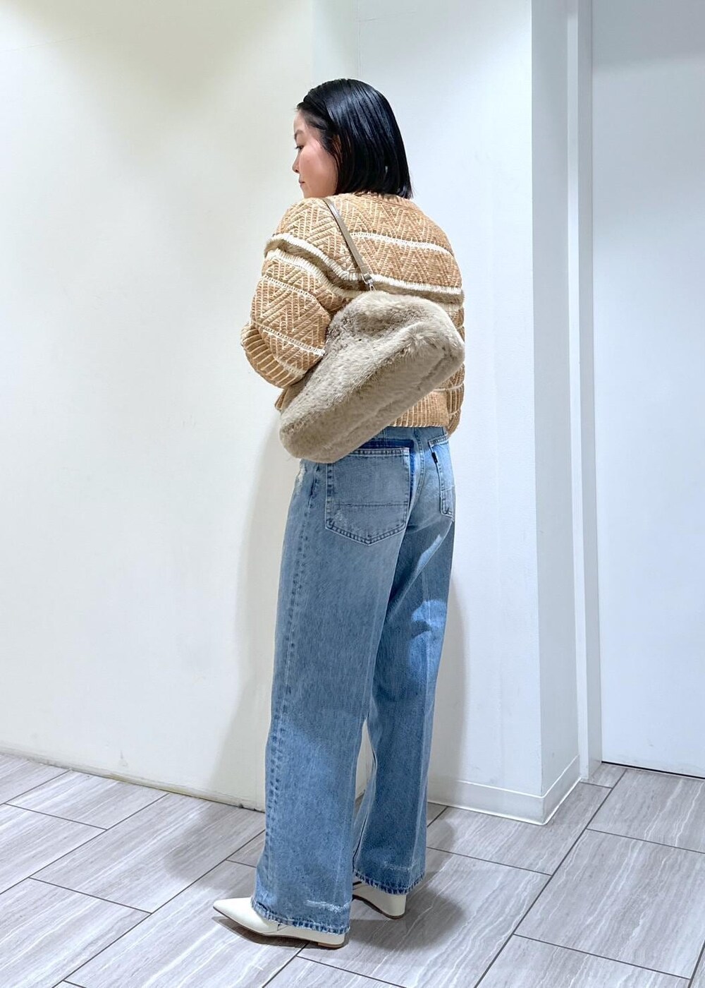 ホワイト系のパンプス、ブルー系のデニムパンツ、ベージュ系のショルダーバッグを着用したレディースの秋コーディネートの3枚目の写真