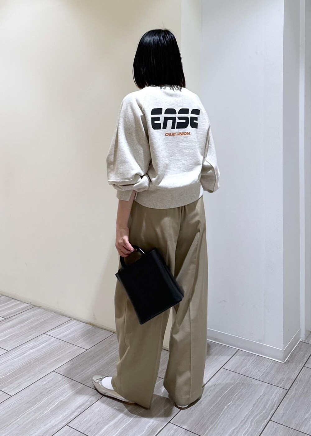 ブラック系のショルダーバッグ、シルバー系のバレエシューズ、ベージュ系のスラックスを着用したレディースの秋コーディネートの3枚目の写真