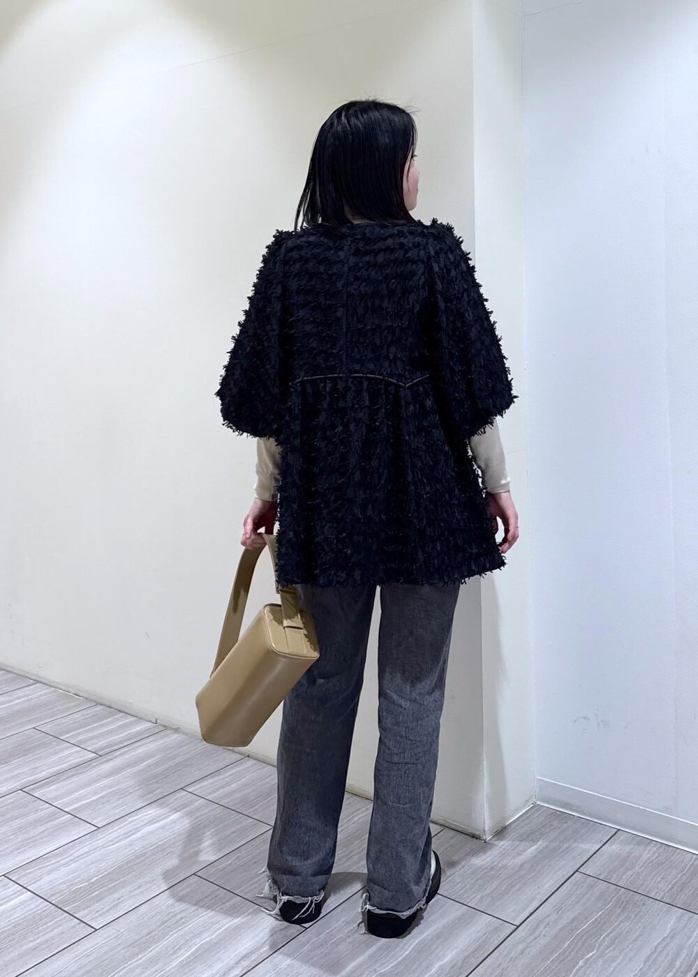 ホワイト系のブーツ、グレー系のデニムパンツ、ベージュ系のハンドバッグを着用したレディースの冬コーディネートの4枚目の写真