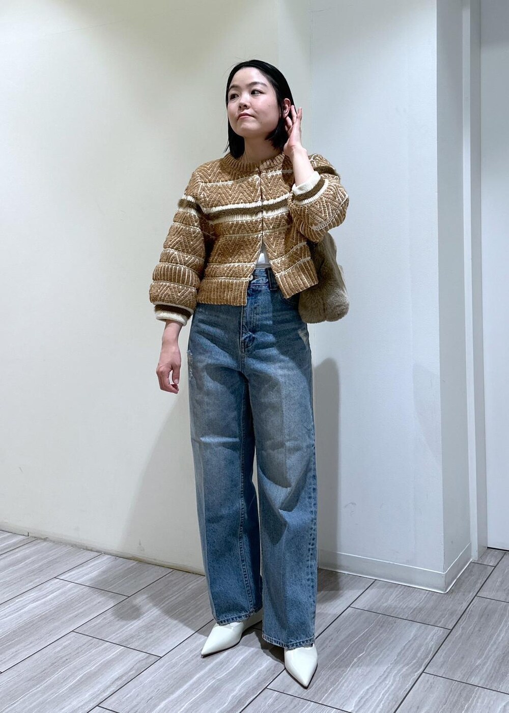 ホワイト系のパンプス、ブルー系のデニムパンツ、ベージュ系のショルダーバッグを着用したレディースの秋コーディネートの6枚目の写真