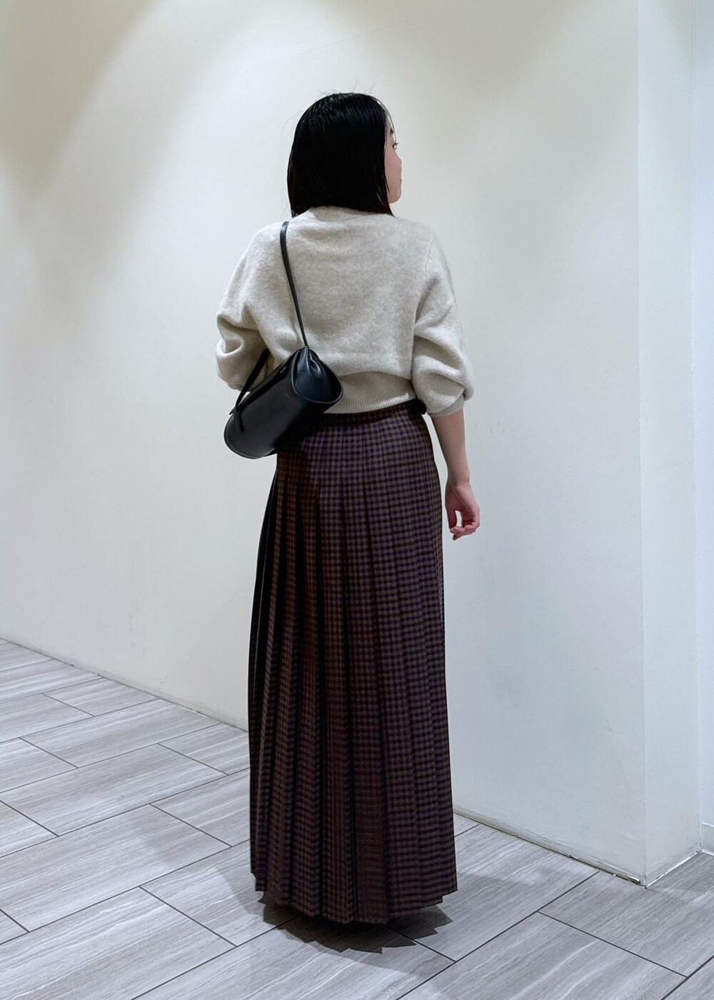 ブラック系のブーツ、ブラック系のショルダーバッグ、ホワイト系のニット/セーターを着用したレディースの秋コーディネートの3枚目の写真