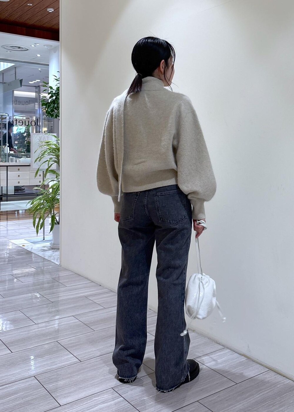 ホワイト系のカーディガン/ボレロ、ブラック系のブーツ、グレー系のデニムパンツを着用したレディースの秋コーディネートの4枚目の写真