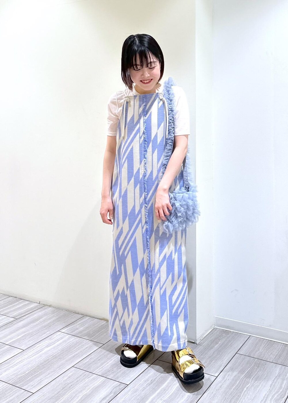 ゴールド系のサンダル、ホワイト系のTシャツ/カットソー、ブルー系のショルダーバッグを着用したレディースの春コーディネートの2枚目の写真