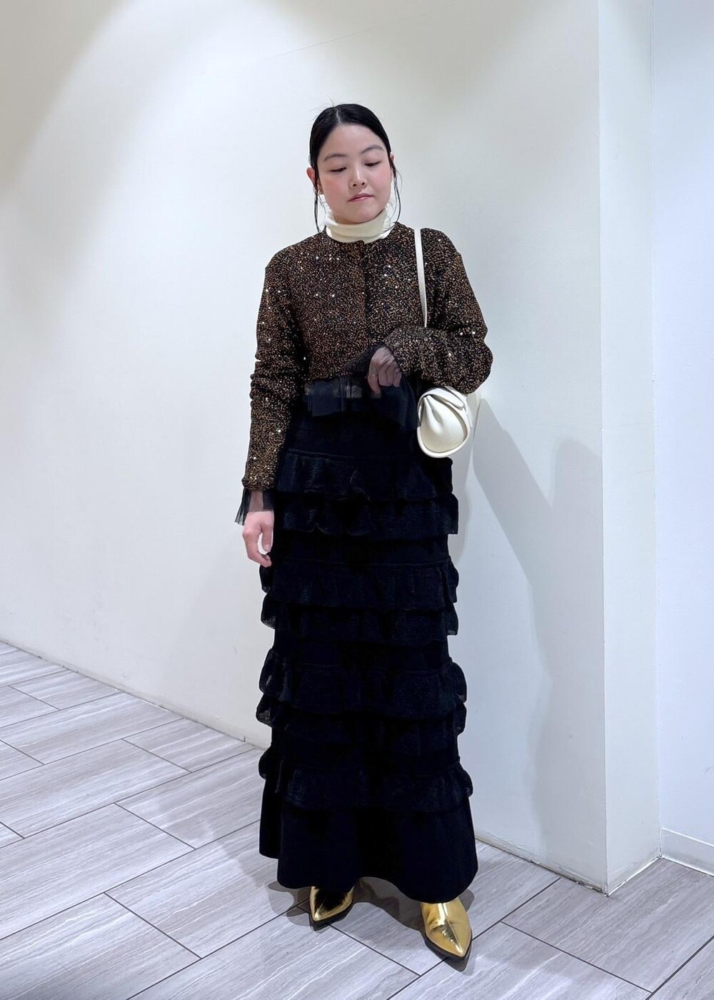 ゴールド系のブーツ、ホワイト系のショルダーバッグ、ブラック系のスカートを着用したレディースの秋コーディネートの5枚目の写真