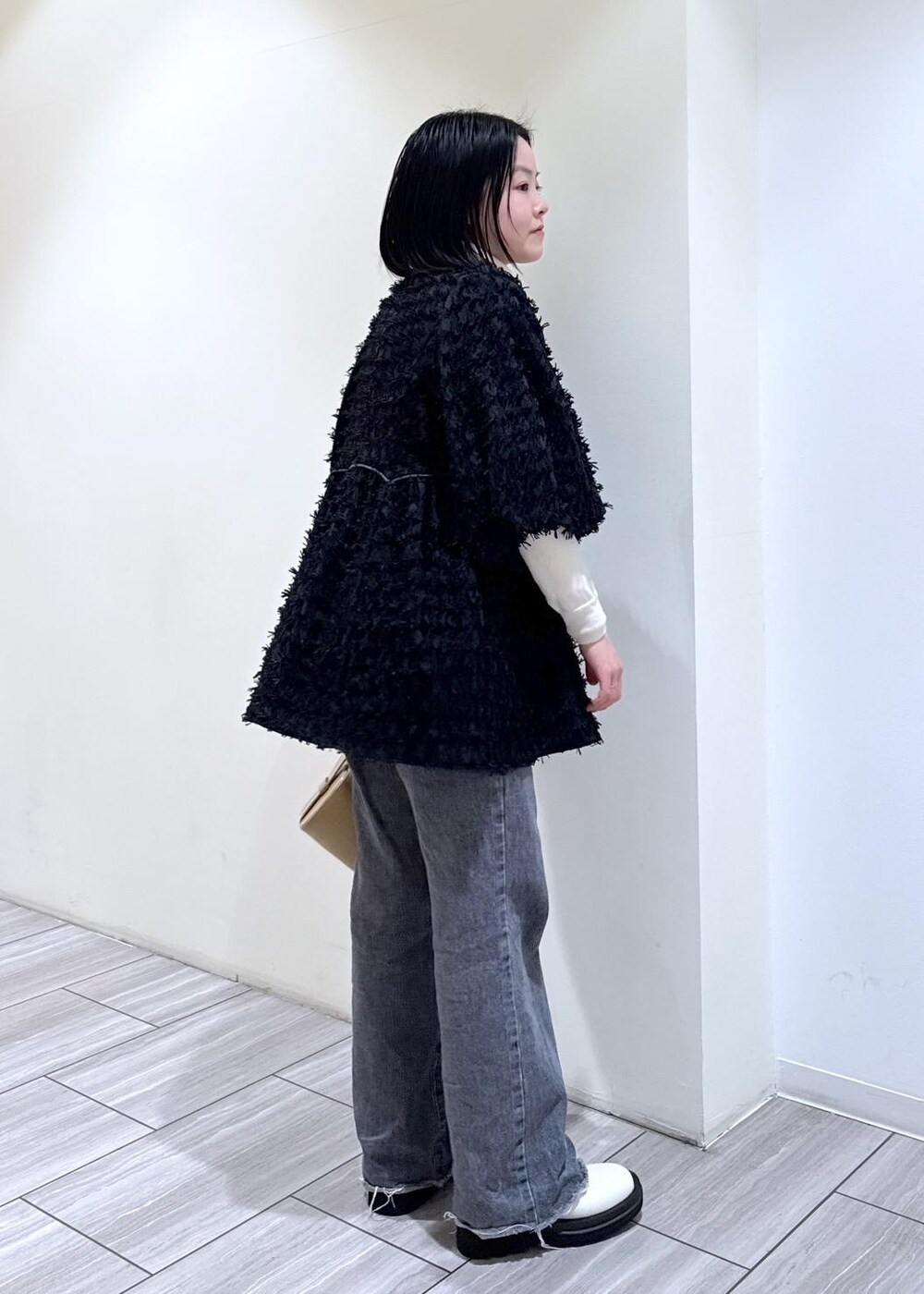 ホワイト系のブーツ、グレー系のデニムパンツ、ベージュ系のハンドバッグを着用したレディースの冬コーディネートの5枚目の写真