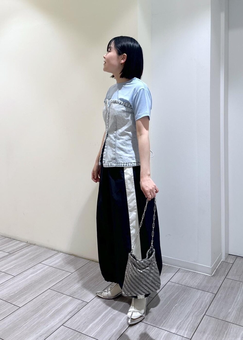 シルバー系のハンドバッグ、シルバー系のサンダル、ブラック系のスカートを着用したレディースの夏コーディネートの2枚目の写真