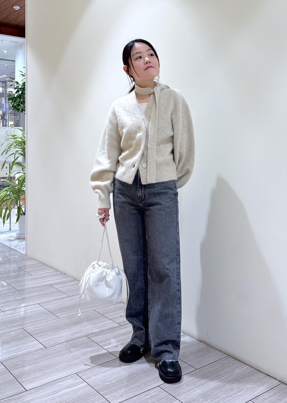 ホワイト系のカーディガン/ボレロ、ブラック系のブーツ、グレー系のデニムパンツを着用したレディースの秋コーディネートの5枚目の写真