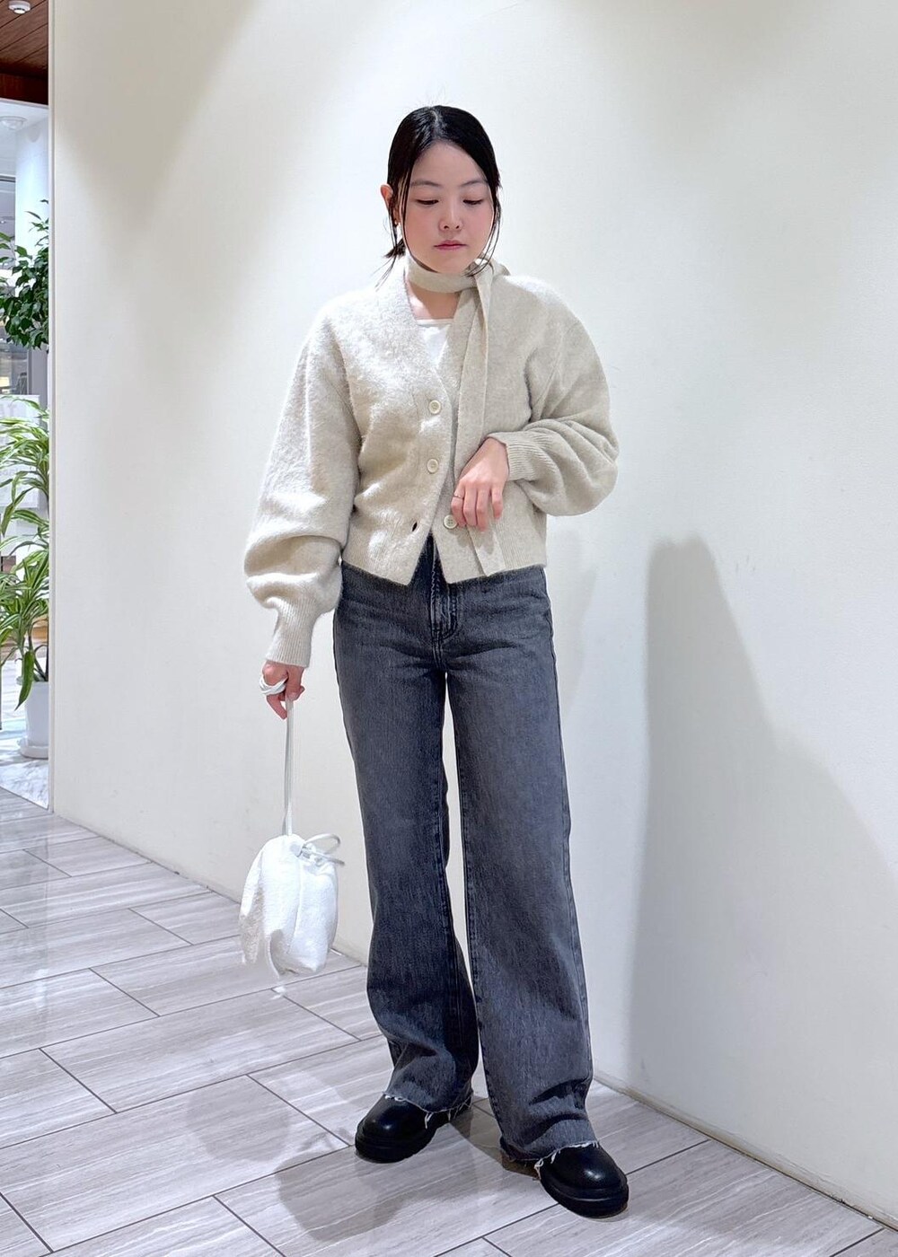 ホワイト系のカーディガン/ボレロ、ブラック系のブーツ、グレー系のデニムパンツを着用したレディースの秋コーディネートの2枚目の写真