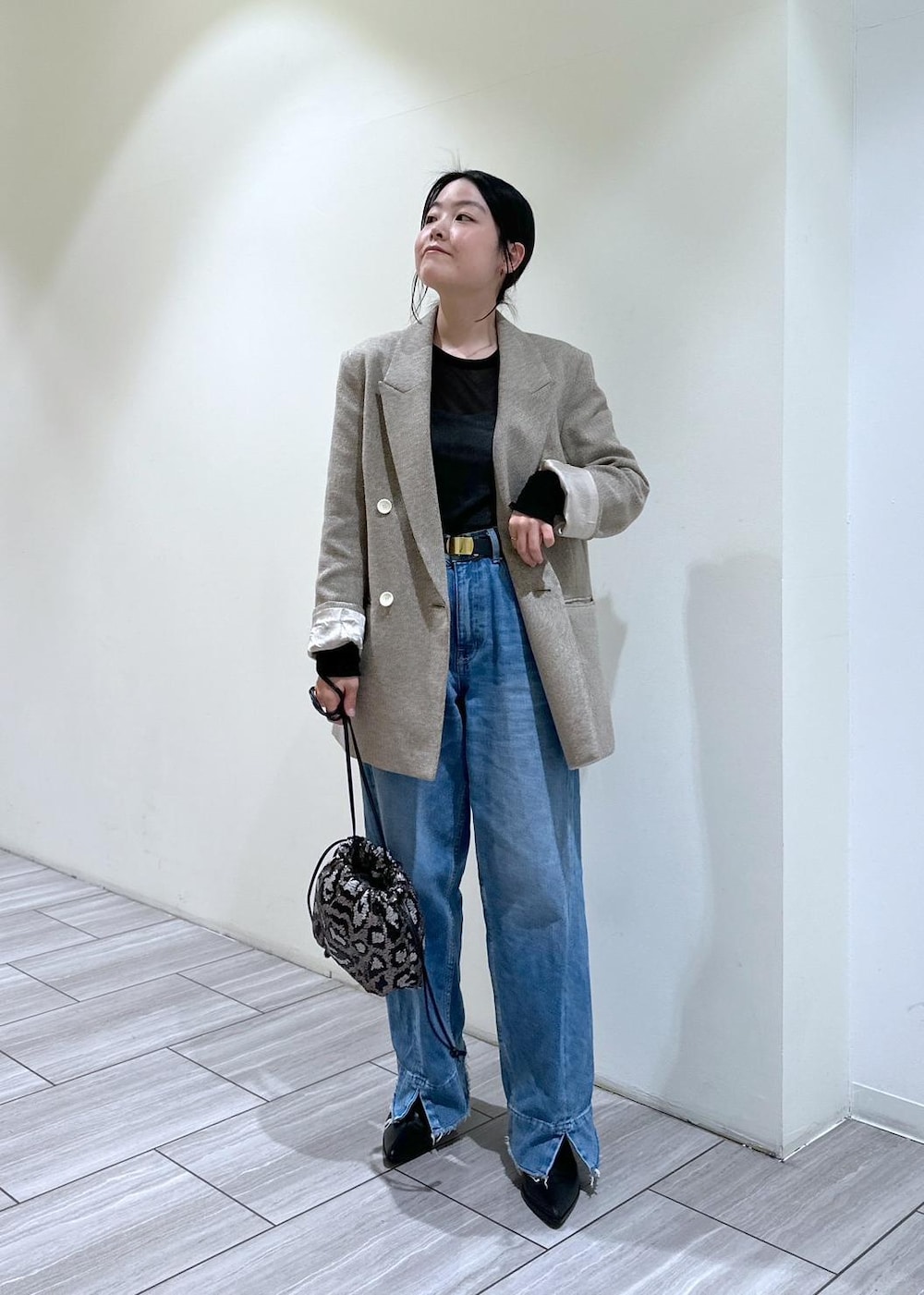 ブルー系のデニムパンツ、ブラック系のブーツ、グレー系のハンドバッグを着用したレディースの秋コーディネートの2枚目の写真