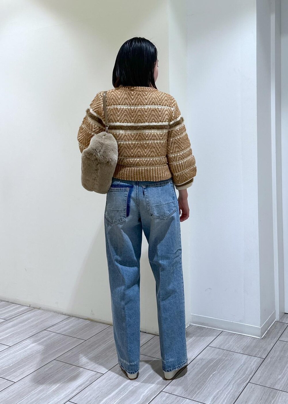 ホワイト系のパンプス、ブルー系のデニムパンツ、ベージュ系のショルダーバッグを着用したレディースの秋コーディネートの4枚目の写真