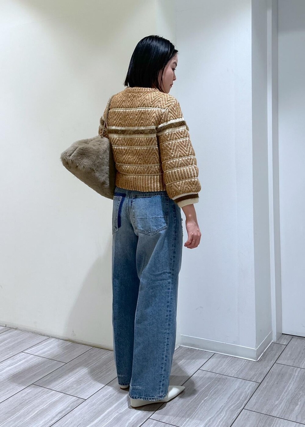 ホワイト系のパンプス、ブルー系のデニムパンツ、ベージュ系のショルダーバッグを着用したレディースの秋コーディネートの5枚目の写真