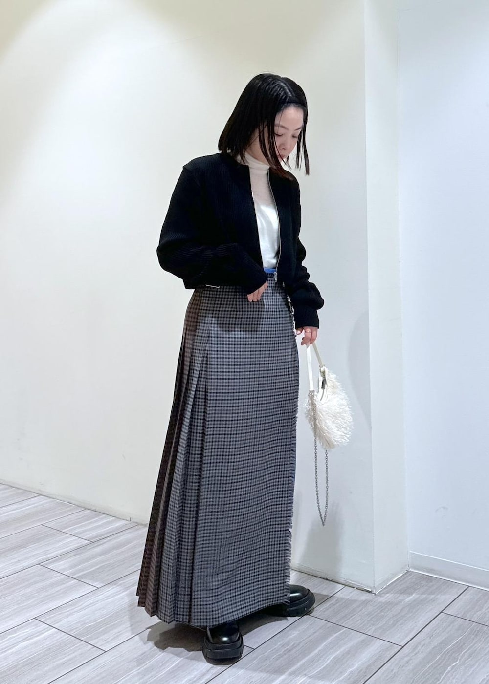 ブラック系のその他シューズ、グレー系のスカート、ホワイト系のニット/セーターを着用したレディースの秋コーディネートの5枚目の写真