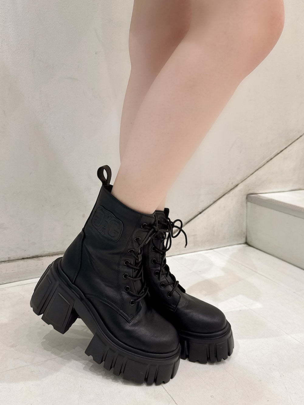 ホワイト系のパーカー、ブラック系のスカート、ブラック系のブーツを着用したレディースの秋コーディネートの5枚目の写真