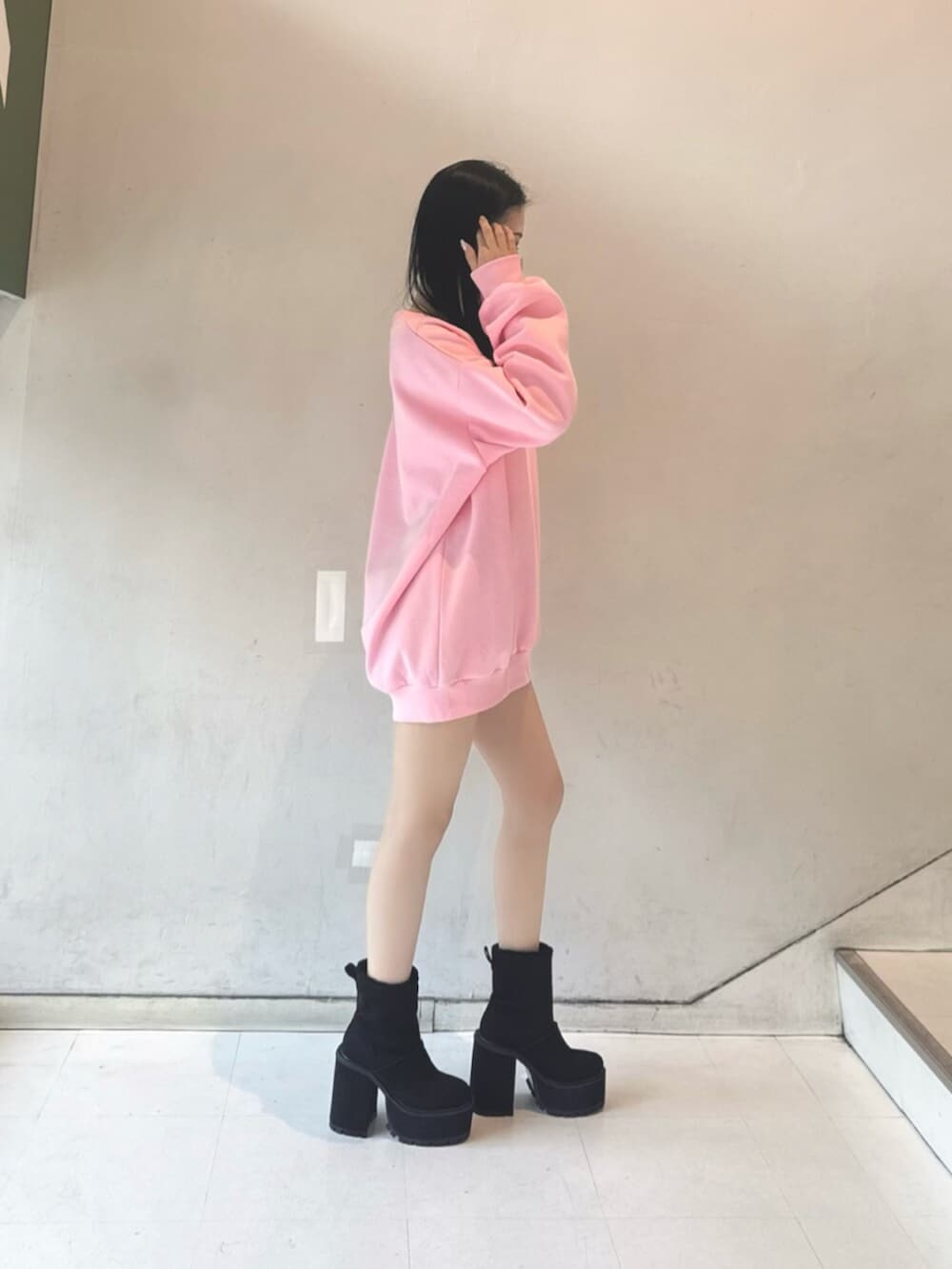 ブラック系のスカート、ブラック系のブーツ、ピンク系のスウェットを着用したレディースの冬コーディネートの2枚目の写真