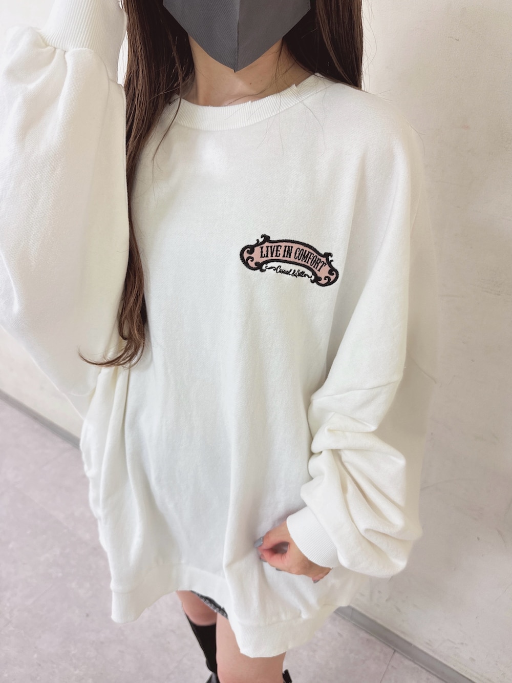 ホワイト系のスウェット、ブラック系のデニムスカート、ブラック系のブーツを着用したレディースの秋コーディネートの4枚目の写真