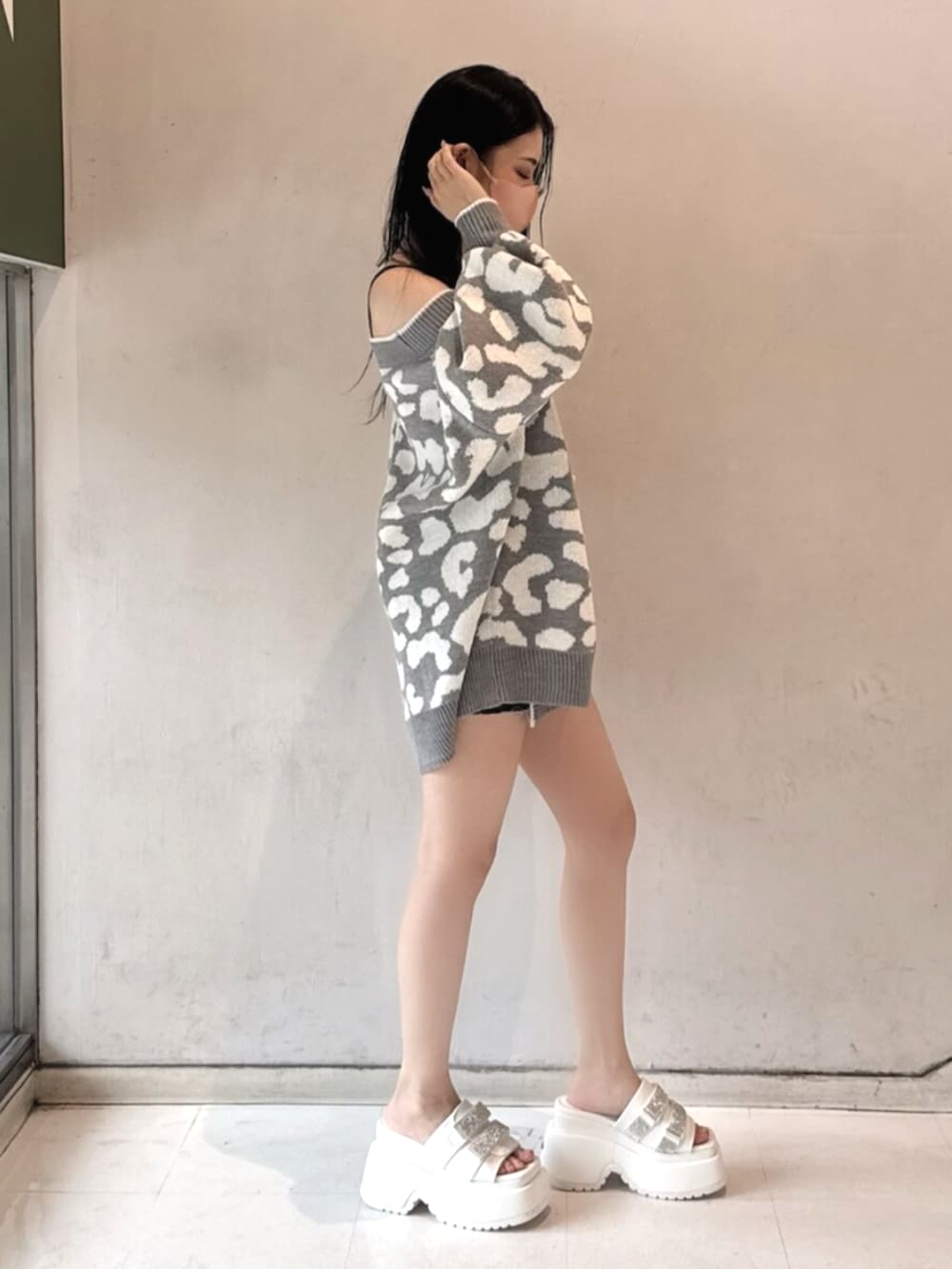 ブラック系のワンピース、グレー系のカーディガン/ボレロ、ホワイト系のサンダルを着用したレディースの春コーディネートの2枚目の写真