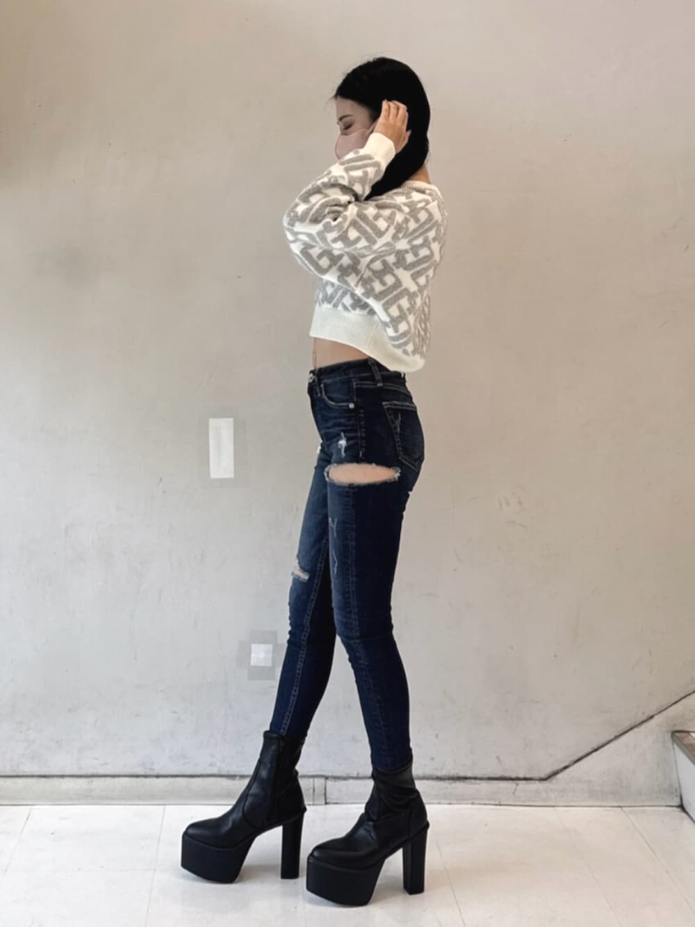 ブラック系のブーツ、ホワイト系のニット/セーター、ブルー系のデニムパンツを着用したレディースの冬コーディネートの2枚目の写真