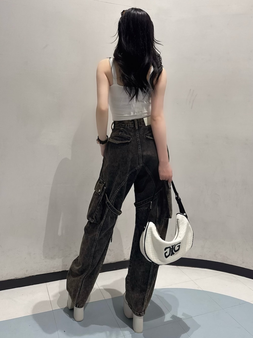 ホワイト系のキャミソール、ブルー系のデニムパンツ、ホワイト系のハンドバッグを着用したレディースの夏コーディネートの3枚目の写真