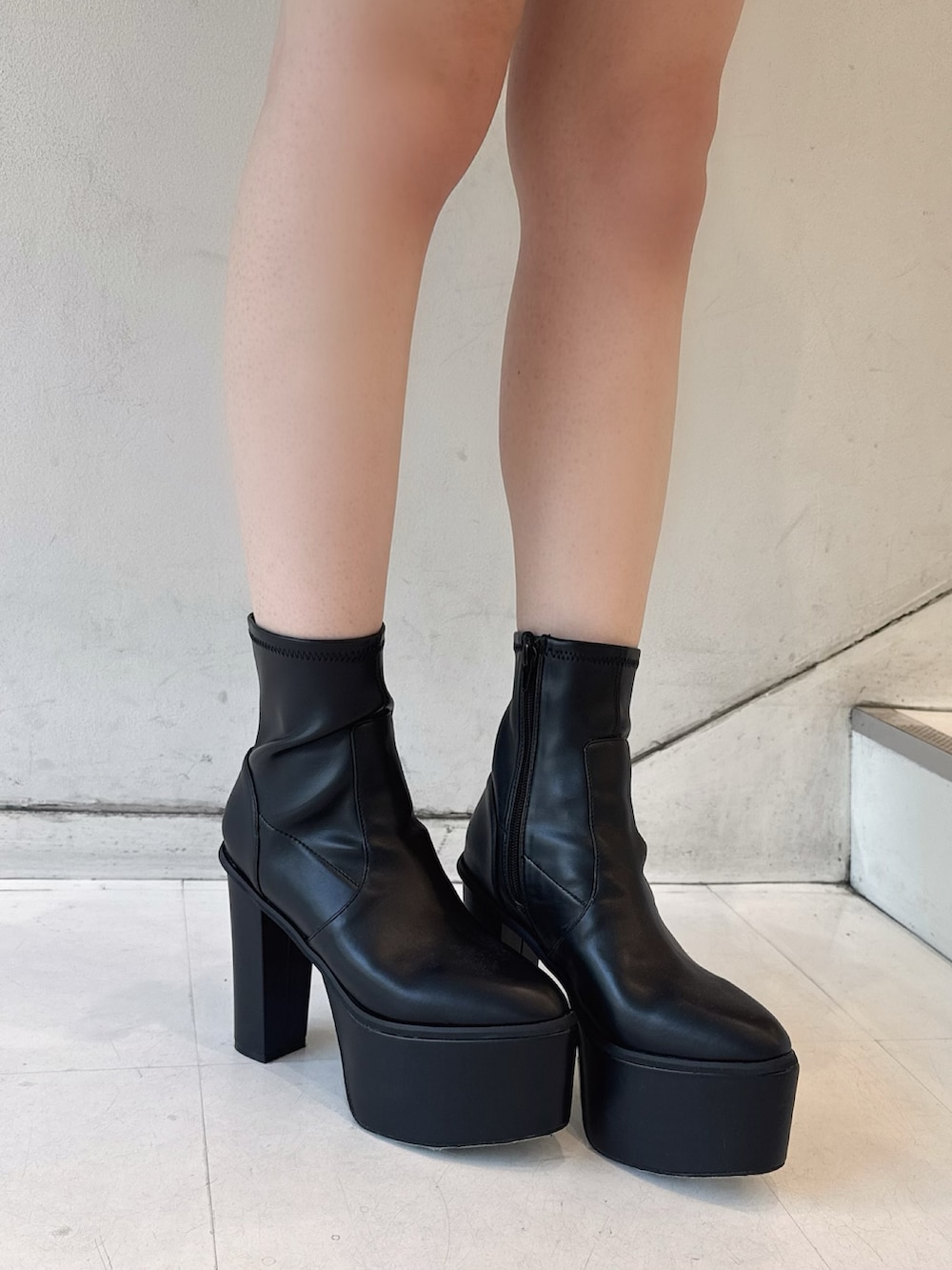 グレー系のスウェット、ブラック系のデニムスカート、ブラック系のブーツを着用したレディースの夏コーディネートの6枚目の写真