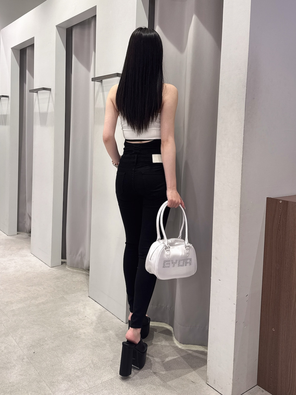 ホワイト系のタンクトップ、ブラック系のデニムパンツ、ブラック系のサンダルを着用したレディースの夏コーディネートの3枚目の写真