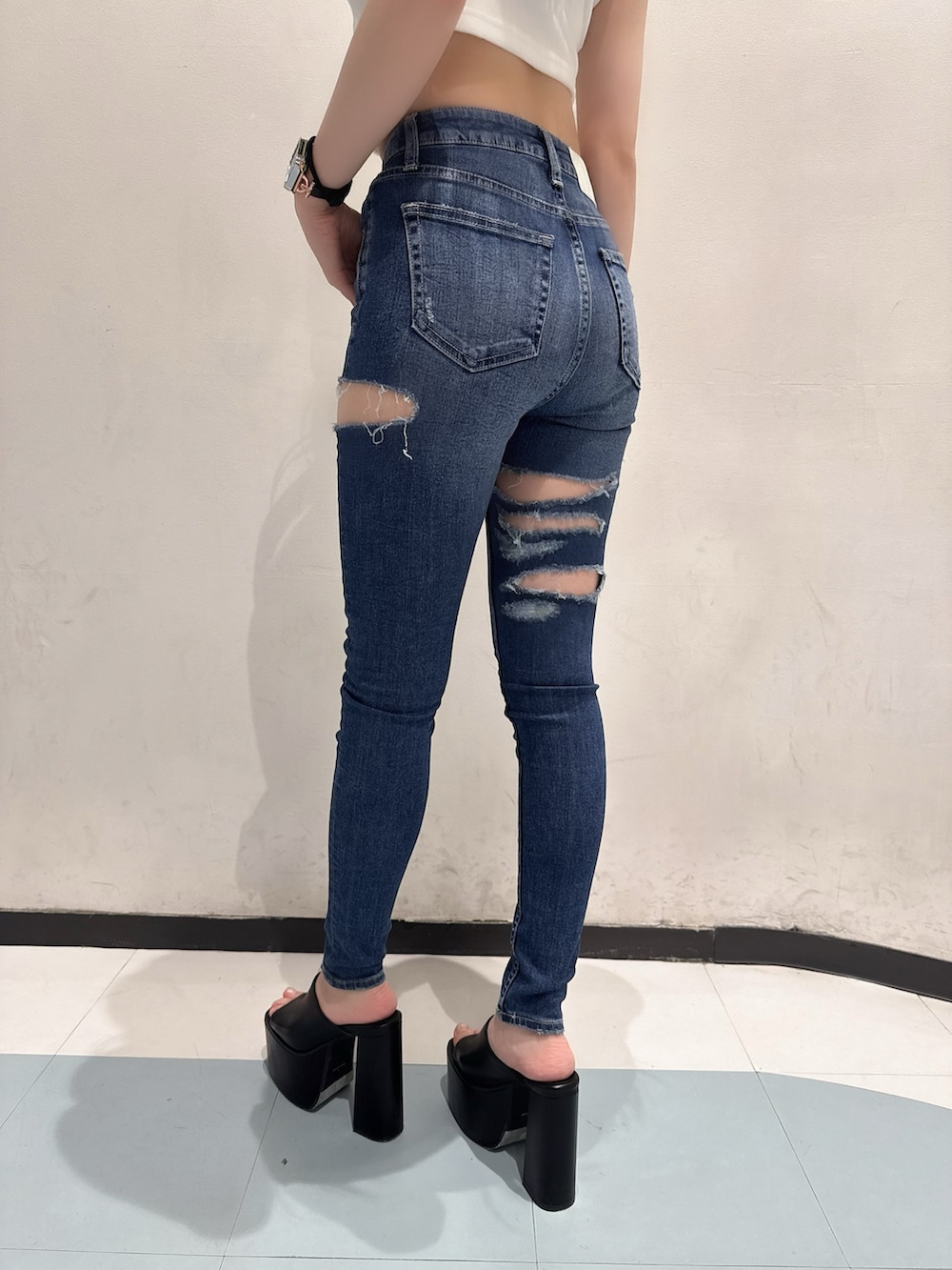 ホワイト系のキャミソール、ブルー系のデニムパンツ、ブラック系のサンダルを着用したレディースの夏コーディネートの5枚目の写真