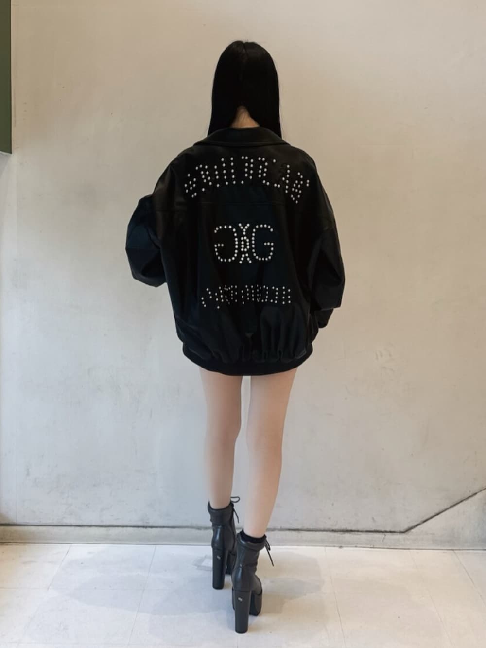 ブラック系のデニムスカート、ホワイト系のTシャツ/カットソー、ブラック系のブルゾンを着用したレディースの冬コーディネートの3枚目の写真