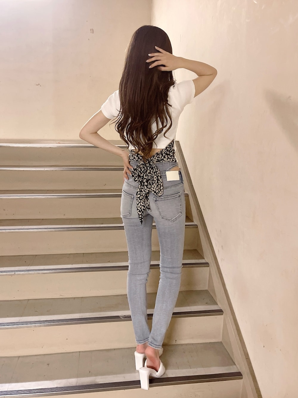 ブラック系のハンドバッグ、ブルー系のデニムパンツ、ホワイト系のTシャツ/カットソーを着用したレディースの春コーディネートの3枚目の写真