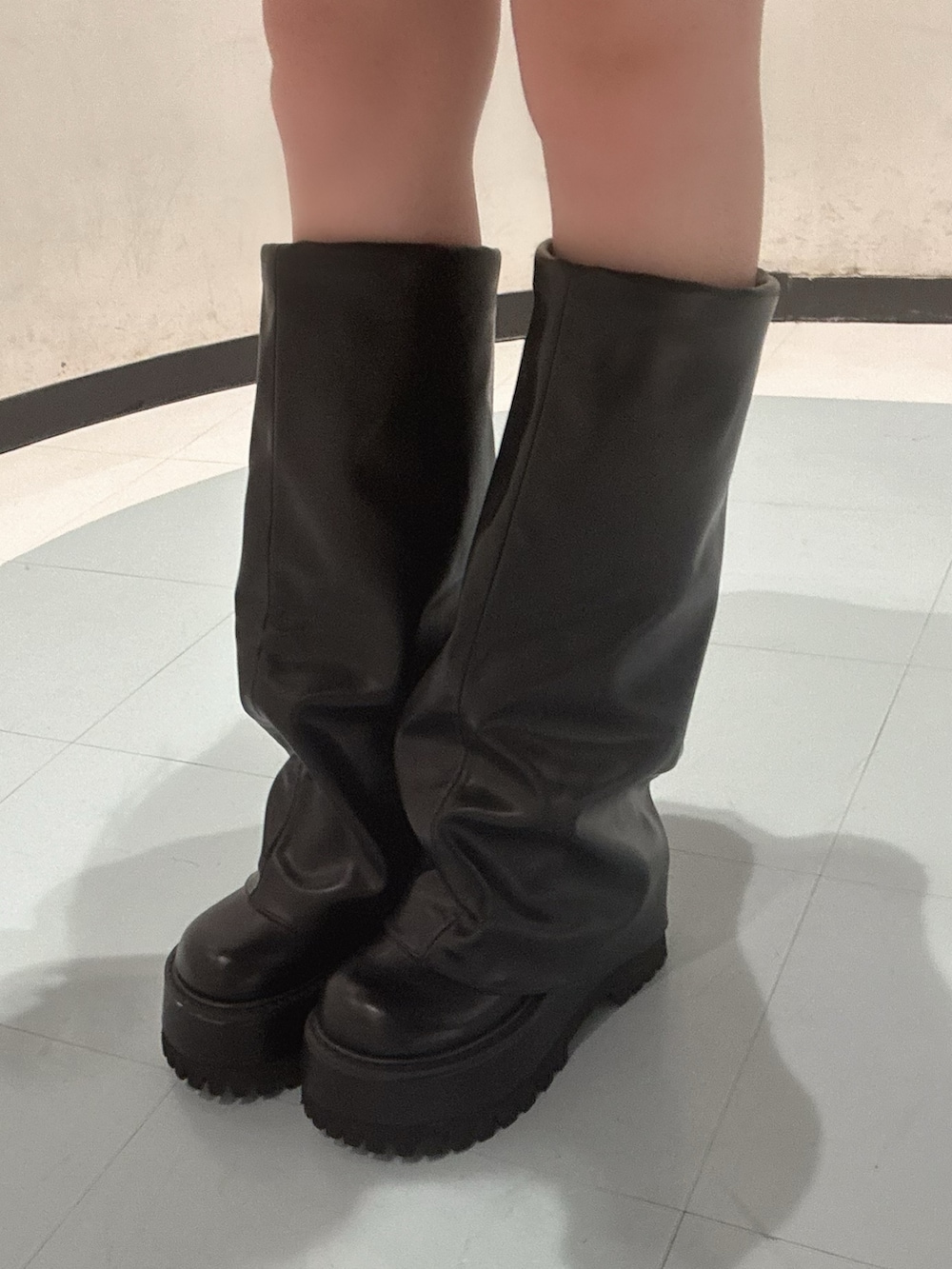 グレー系のニット/セーター、ブラック系のスカート、ブラック系のブーツを着用したレディースの秋コーディネートの6枚目の写真